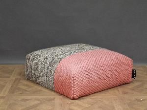 a pink and grey pouft sitting on top of a wooden floor