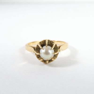 gros plan d'une bague en or avec une perle au centre