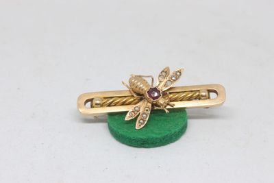 yellow gold bee hair clip on a green base with a diamond center