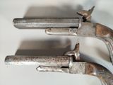 pair of antique flinted pistols on display on a white surface