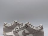 La Nike Dunk Low est une chaussure en daim gris clair dotée d'une semelle blanche.