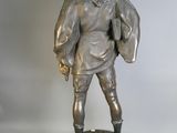statue en bronze représentant un homme coiffé d'un chapeau et vêtu d'une veste, posée sur un socle