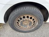 a dirty tire on the side of a white car