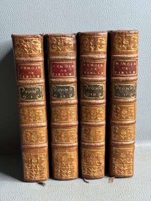 quatre vieux livres sont alignés sur une étagère adossée au mur