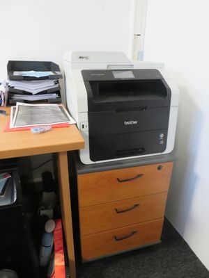 a printer sitting on top of a desk next to a filing cabinet