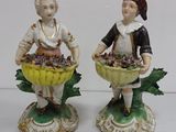 pair of figurines of a boy and a girl with baskets of grapes