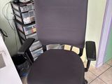 a black office chair sitting in front of a computer desk