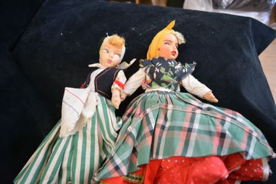 two dolls that are sitting on a black pillow