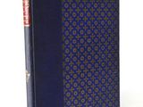 an old book with a blue cover sitting on top of a white table