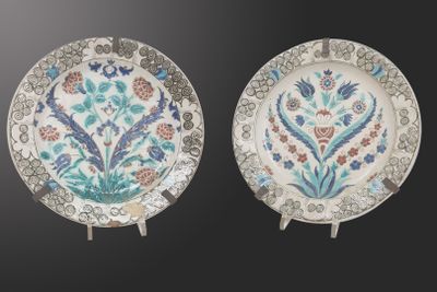 two plates with floral designs on them on a black background