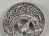 an image of a silver broochle with a star on it