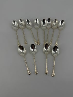 a set of six silver spoons on a white surface