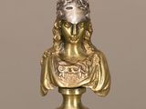 une statue en or représentant une femme, posée sur une table en verre