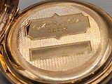 a gold pocket watch sitting on a table next to a clock