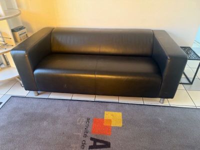 a black leather couch sitting in a room with a rug on the floor