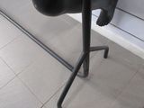 a black sculpture of a person with a leg on a stand