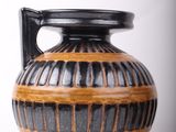 a black and brown vase sitting on a white surface