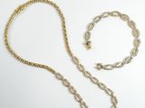 deux morceaux de chaîne en or et un collier posés sur une surface blanche
