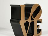 a black and gold love sculpture on a white surface