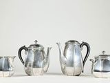 quatre théières en argent et une cafetière sur une table