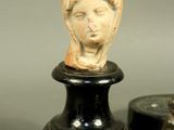 a small statue of a woman on a pedestal next to a coin