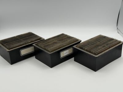 three black boxes with wooden lids on a white surface