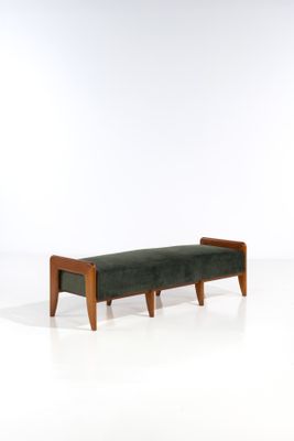 le banc est en bois et dispose d'une assise rembourrée verte