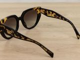 leopard print sunglasses on a wooden table with a white background