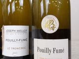 three bottles of white wine are lined up on a table