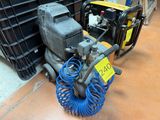 un tuyau bleu posé par terre à côté d'un petit compresseur d'air