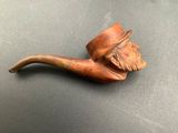 an old pipe with a man ' s face on it sitting on a table