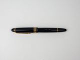 a black pen with gold trim sitting on top of a white surface