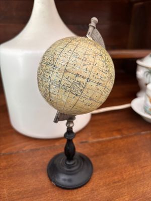 un petit globe posé sur une table à côté d'un vase