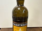 une photo d'une bouteille de Chartreuse posée sur une table en bois