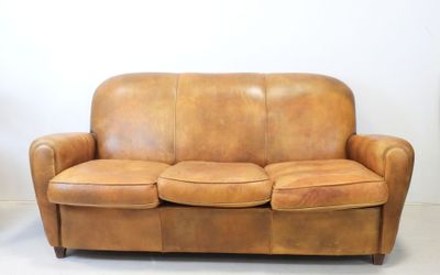 a brown leather couch sitting on the floor in a room