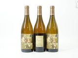 trois bouteilles de vin posées les unes à côté des autres sur une surface blanche