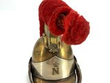 a small bell with two red flowers on top of it