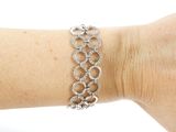 a woman ' s arm with a silver bracelet on it