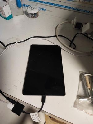 a tablet computer sitting on a desk with a charger