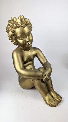 statue en or représentant un garçon assis par terre, les mains posées sur les genoux