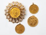 un gros plan sur trois pièces d'or et un pendentif posés sur une surface blanche