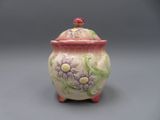 un pot en céramique orné de fleurs, posé sur un fond gris