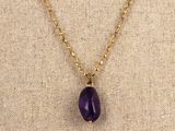 a gold chain necklace with a purple stone pendant on it
