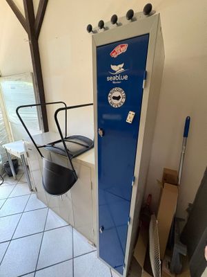 a blue locker in the corner of a room next to a chair