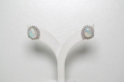 une paire de boucles d'oreilles en oplite et diamants, présentées sur un socle blanc