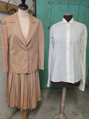 deux mannequins devant une porte verte et une chemise blanche posée sur un support à mannequin