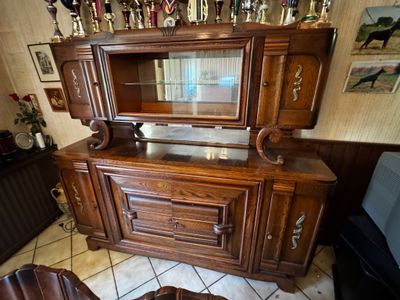 une armoire en bois avec une porte vitrée et une table avec deux chaises