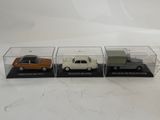 three small toy cars are in a display case on a white surface