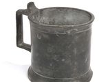 a small metal cup with a handle on a white surface
