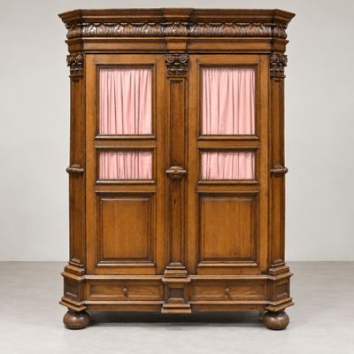 une armoire ancienne en bois surmontée de rideaux roses